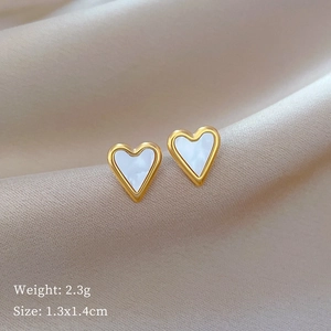 Macro shot of heart-shaped gold shell earrings on beige satin with size 1.3x1.4cm details