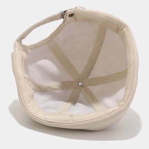 Minimalist beige cotton brimless cap showing reinforced seams and adjustable metal strap