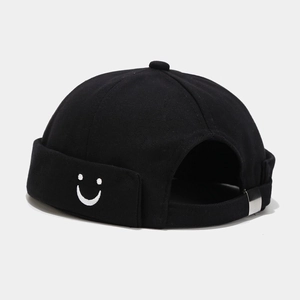 Detail of black cotton docker hat featuring white smiley face embroidery and metal buckle
