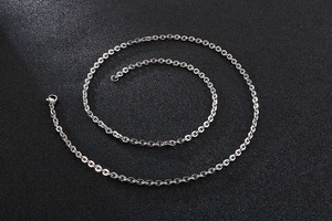 Macro shot of silver metal O-chain necklace links arranged in a spiral on black background