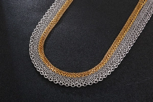Macro detail of multi-layered mixed gold and silver cable chain necklace on black surface