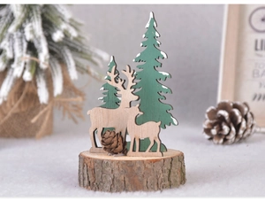 Close-up of wooden reindeer and snow-covered pine trees on a natural bark base