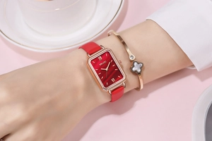 Elegant women's square gold watch with red leather strap shown on a wrist