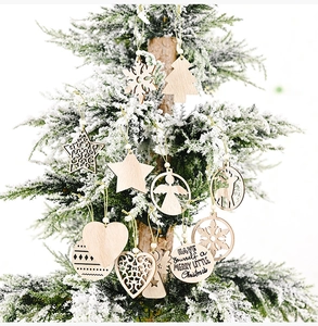 Detailed view of laser-cut wooden Christmas ornaments hanging on a snowy pine branch