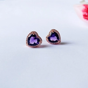Macro detail of heart-shaped purple zircon earrings with rose gold halo setting