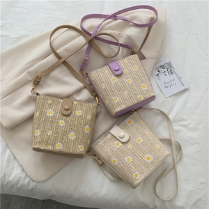 Close-up of woven bucket bags with daisy prints in purple, khaki and cream white