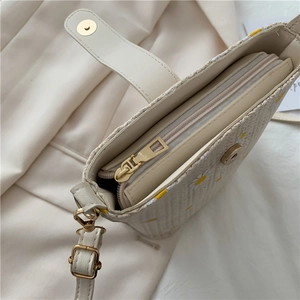 Detail view of daisy straw bag featuring secure magnetic clasp and smooth zipper closure