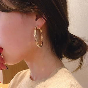 Gold-plated C-shaped hoop earrings featuring hollow rhinestone design on female model