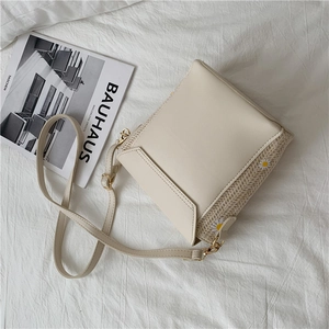 Detail of straw bucket bag with daisy embroidery and smooth PU leather strap