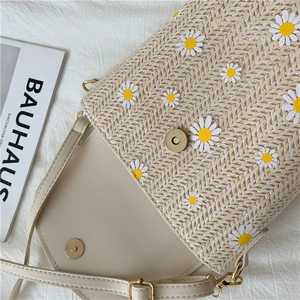 Close-up of beige woven bucket bag with daisy embroidery and metal magnetic clasp