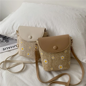 Detail of hand-woven straw bucket bag with daisy patterns and soft PU leather flap