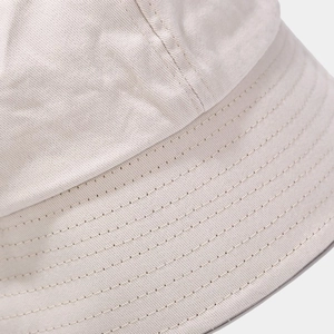 Detailed close-up of beige cotton bucket hat with fine parallel stitching on the brim