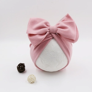 Soft pink baby bow turban hat made of cashmere-like fabric on a display stand