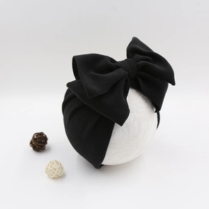 Close-up of a large black bow baby turban hat on a white display model head