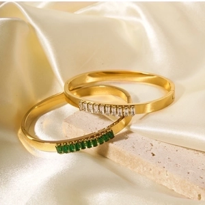 Detailed close-up of gold plated stainless steel bangles with white and green zircons