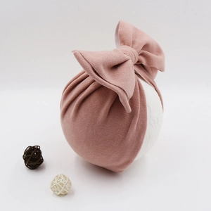 Detail of baby turban hat in dusty rose velvet with a large decorative bow