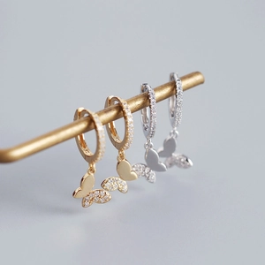 Macro shot of silver and gold butterfly hoop earrings with sparkling diamond accents