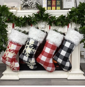 Plaid Christmas stockings with snowflake patterns hanging on a decorated fireplace