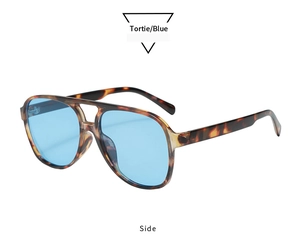 Detail view of tortoiseshell double-bridge sunglasses with blue lenses and wide temples