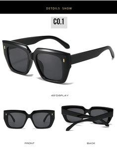 Detail view of large square black sunglasses with gold metal studs on a white background