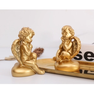 Détail de figurines d'anges dorés en résine avec des ailes sur un plateau déco