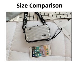 Silver mini suitcase crossbody bag size comparison with smartphone on patterned background
