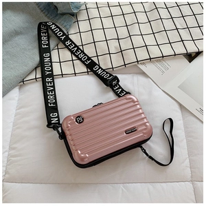 Close-up of pink mini suitcase crossbody bag with Forever Young wide strap