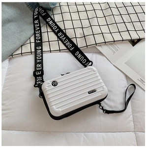 Detail view of the white hard shell mini suitcase bag with Forever Young strap on a bed
