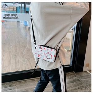 Detailed back view of a white mini suitcase crossbody bag with red floral pattern and strap