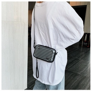Detailed view of silver mini suitcase crossbody bag with metallic ridges and nylon strap