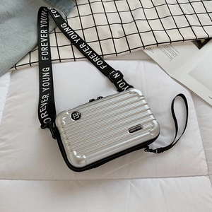 Detailed close-up of a silver mini suitcase crossbody bag with Forever Young strap