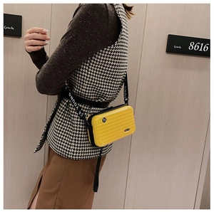 Detail of yellow hardshell mini suitcase crossbody bag with adjustable wide strap