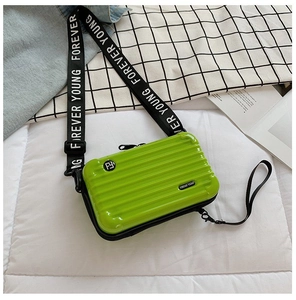 Detail of a neon green mini hardshell suitcase bag with striped texture and logo strap