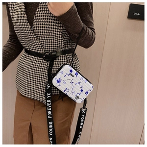 Close-up of mini suitcase bag with blue floral print and Forever Young logo strap
