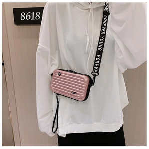 Detail of pink hard shell mini suitcase bag with wide letter printed shoulder strap