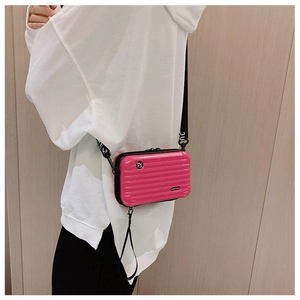 Macro detail of a bright pink mini suitcase crossbody bag with wave texture and logo