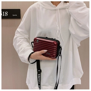 Detail of burgundy hard shell mini suitcase crossbody bag with Forever Young strap
