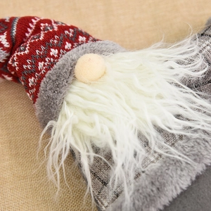 Red knitted Christmas forest gnome ornament with white beard on brown fabric background