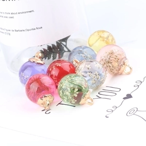 DIY colorful glass ball pendants with dried flowers and gold metal caps on white background