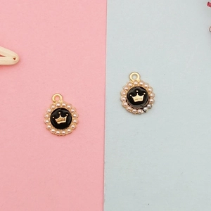 Detail of round crown charms with black enamel, gold base and white imitation pearls