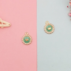 Macro detail of round mint green enamel pendant with golden crown and pearl edge