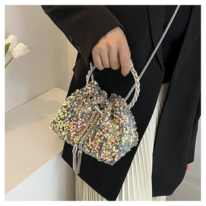 Detail of colorful sequin bucket bag with chain strap held by a model in a fashion outfit