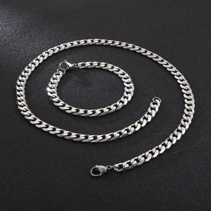 Polished silver stainless steel Cuban link chain necklace and bracelet set on dark background