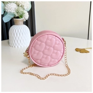 Detailed shot of pink heart-quilted round crossbody bag with gold chain and flower pendant