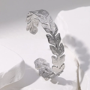 Minimalist silver stainless steel open leaf bracelet displayed on white textured stone