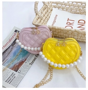 Detail of pink and yellow quilted heart bags with pearl handles and gold chain straps