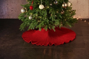 Detail showing the thick red knit texture of the Christmas tree skirt on the floor