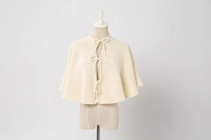 Detailed view of cream white knitted mini tree skirt with three delicate tie-up bows