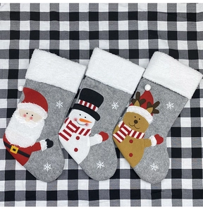 Detailed view of three grey felt Christmas stockings with Santa, Snowman, and Reindeer motifs