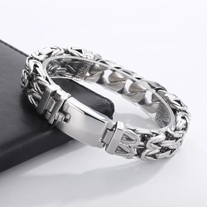 Detail of silver stainless steel woven chain bracelet with vintage pattern on black leather